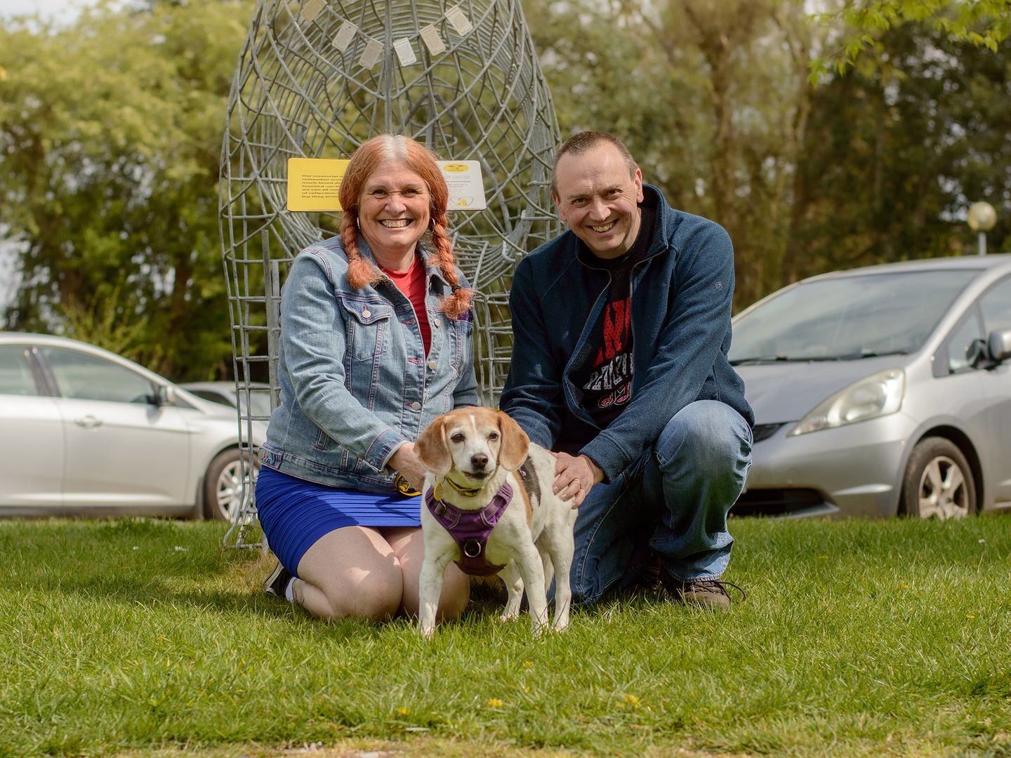 Tilly the beagle poses next to her adopters Adam and Donna